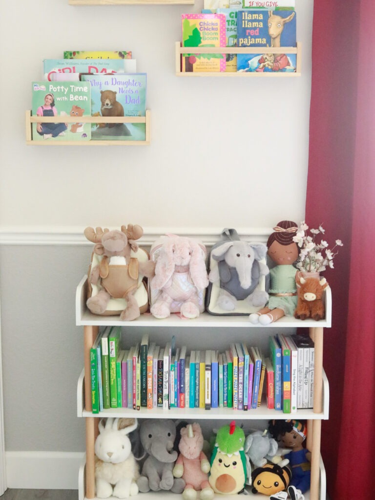 Moonkie Hug n Go toddler backpack (Elephant, Reindeer, Bunny) displayed in a child's room with books and other stuffed animals, showing them as a comforting part of toddler development.