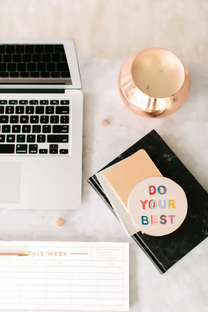 Laptop computer and physical paper calendar on a bright desk, symbolizing the blend of digital AI tools and traditional family organization